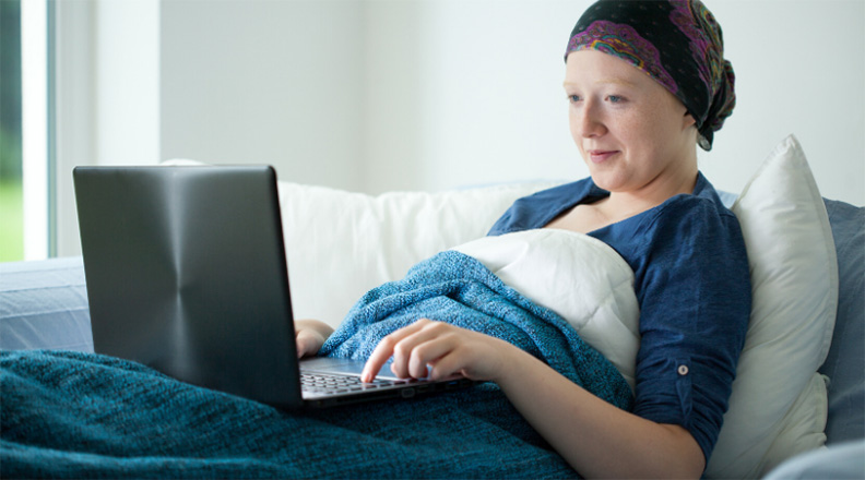 Woman with cancer on a computer in bed