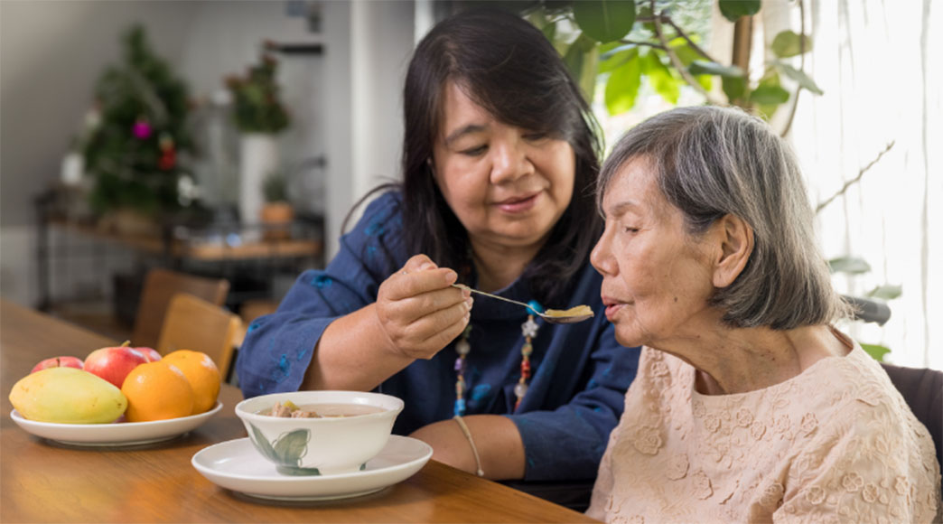 A woman feeding an older woman who has dysphagia
