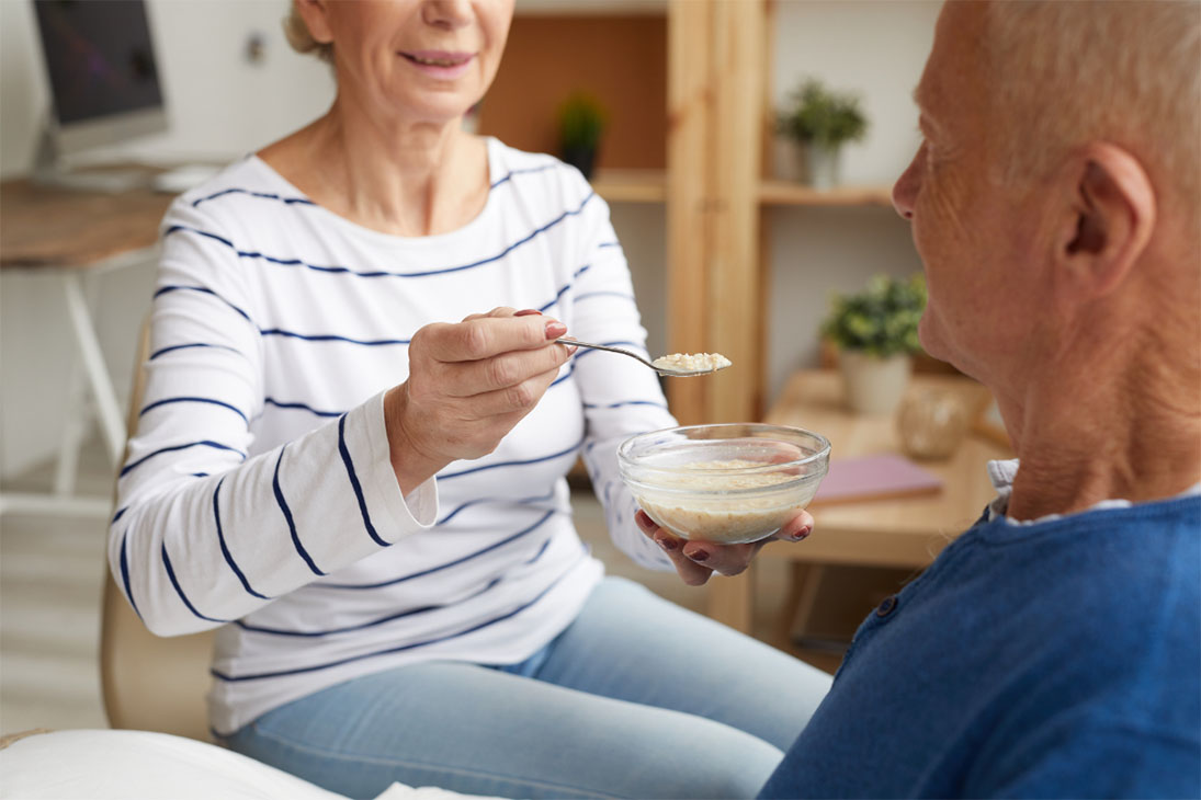 A woman feeding her ailing husband
